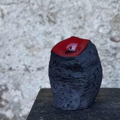 Skulptur #13; rechteckige Skulptur aus schwarzem Ton, Oberseite rot glasiert, seitlich Textur von Rosendornen